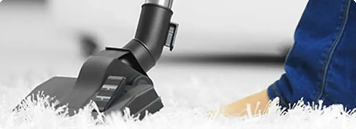 Close-up of a professional vacuuming a white carpet in Harborcreek.